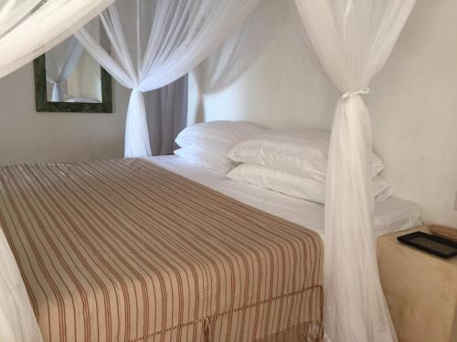 a bedroom with a bed with white drapes at Mangrove House in Lamu
