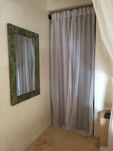 a mirror hanging on a wall next to a curtain at Mangrove House in Lamu
