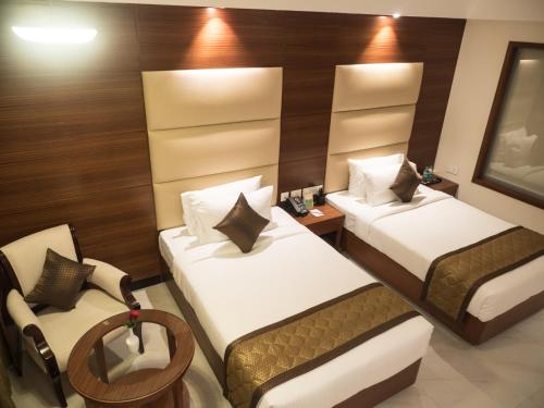 a hotel room with two beds and a chair at MM Legacy - A Bergamont Hotel, Kanchipuram in Kanchipuram