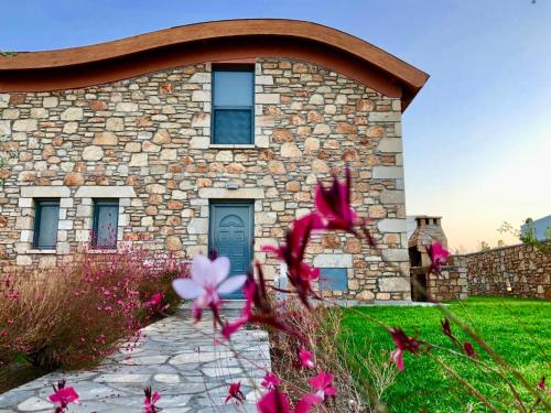 a stone house with pink flowers in front of it at Estrella Villas in Lardos