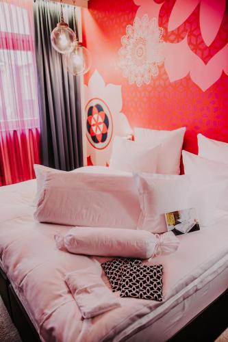 a bedroom with a white bed with pink walls at Hotel & Restaurant Heyligenstaedt in Gießen