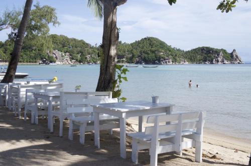 a row of white tables and chairs on the beach at Assava Dive Resort - SHA Plus in Koh Tao