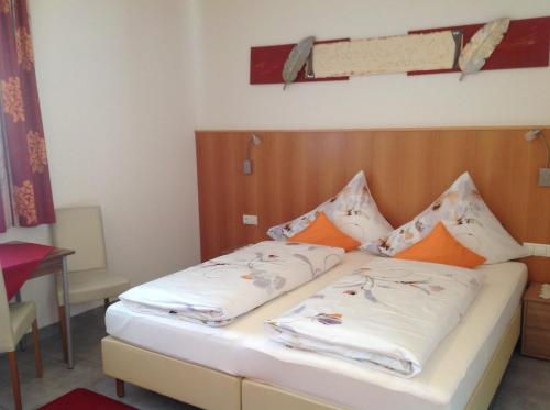 a bedroom with a bed with white sheets and orange pillows at Apart Garni Lais in Galtür