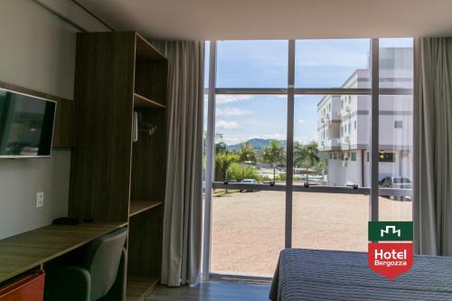 a hotel room with a bed and a large window at Hotel Bergozza in Rio do Sul