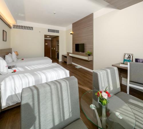 a hotel room with two beds and a glass table at The Nalod Da Nang in Da Nang