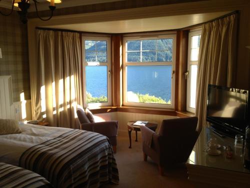 オニックにあるThe Lodge On The Loch Onichのベッド1台、椅子2脚、窓が備わる客室です。