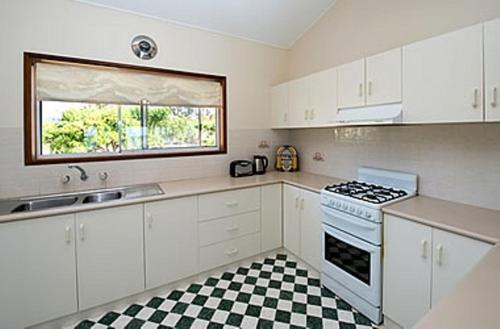 a kitchen with white cabinets and a black and white checkered floor at Barmera Lake Resort Motel in Barmera