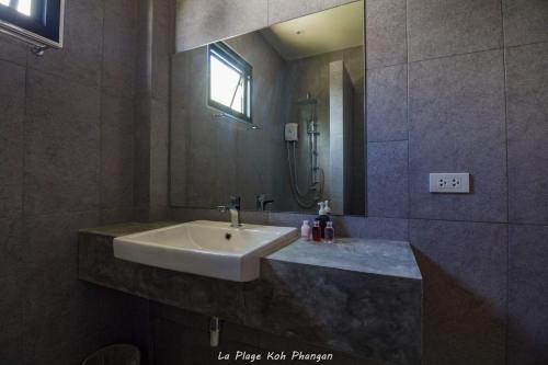 a bathroom with a sink and a mirror at la plage resort & beach club in Baan Tai
