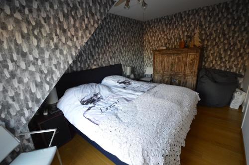 een groot bed in een slaapkamer met een muur bij Ars Vivendi in Moerbeke
