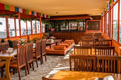 un restaurante con mesas y sillas de madera y ventanas en Hotel Nepalaya, en Katmandú