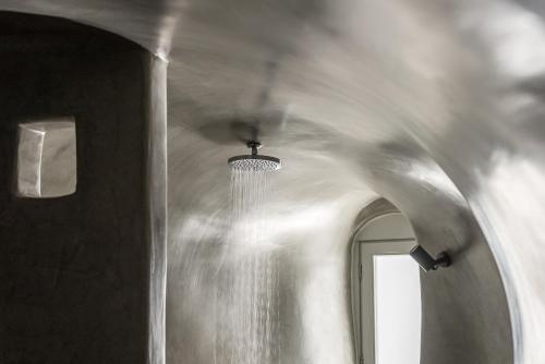 a white hallway with a ceiling with a light fixture at Cocoon Suites in Imerovigli