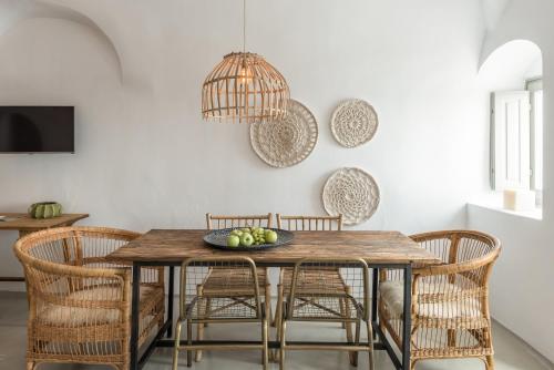 a dining room with a wooden table and rattan chairs at Cocoon Suites in Imerovigli