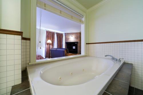 a bath tub in a bathroom with a large mirror at La Remontée Appartements Hôtel in La Malbaie