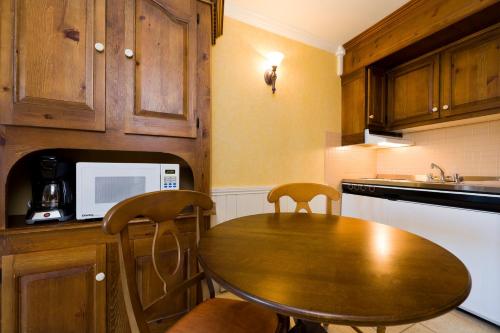 a kitchen with a wooden table and two chairs at La Remontée Appartements Hôtel in La Malbaie