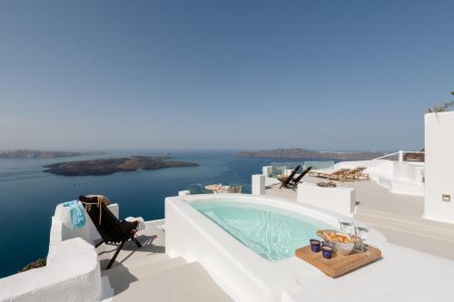 a pool on the side of a house with a view of the ocean at Cocoon Suites in Imerovigli