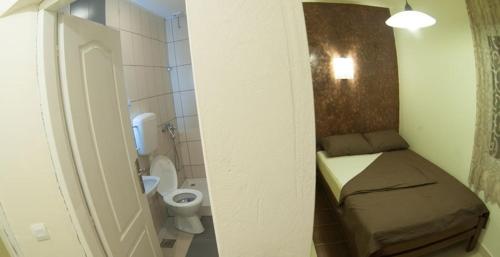 a small bathroom with a bed and a toilet at Prenoćište Trio in Vranje