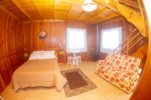 1 dormitorio con 1 cama y 1 sofá en Café e Cabanas Lenha no Fogo en Urubici