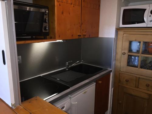 une cuisine avec un évier et un micro-ondes dans l'établissement LE CHRISTIANIA Les bergers, à L'Alpe-d'Huez