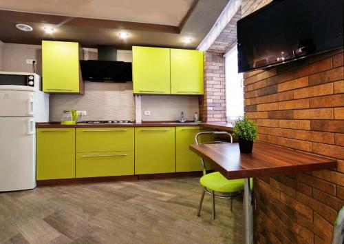 a kitchen with yellow cabinets and a wooden table at Luxury Loft в центре Полтавы in Poltava