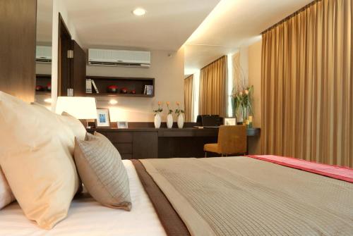a hotel room with a bed and a desk with a desk at The Narathiwas Hotel & Residence Sathorn Bangkok in Bangkok