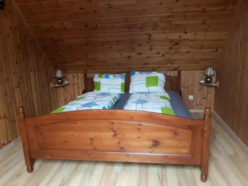1 dormitorio con 1 cama en una habitación de madera en Alyvos, en Ignalina