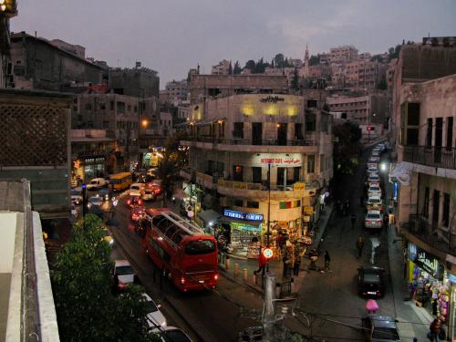a busy city street with cars and a red bus at Cliff Hostel in Amman