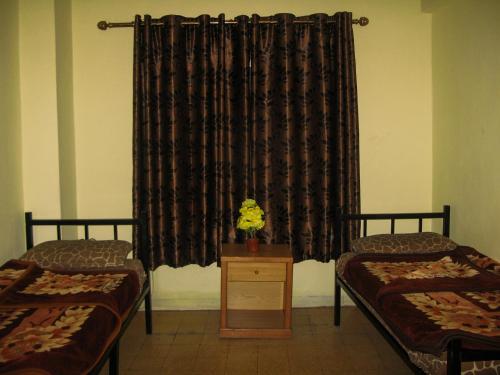 a room with two beds and a window with curtains at Cliff Hostel in Amman