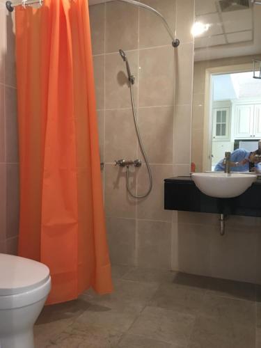 an orange shower curtain in a bathroom with a sink at Cozy and Bright - Trillium Downtown Surabaya in Surabaya