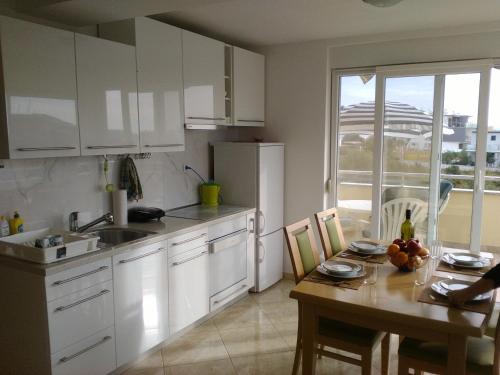 een keuken met witte kasten en een houten tafel met een tafel bij Apartament M & E in Vodice