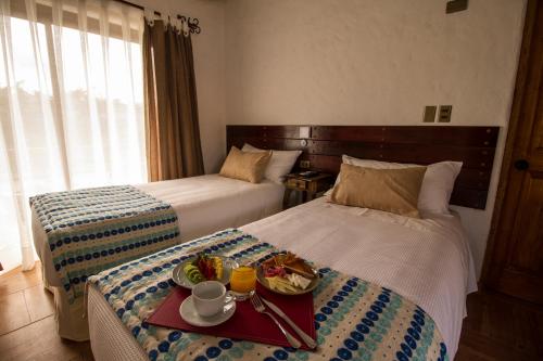a hotel room with two beds with a tray of food at Hotel El Molino in Santa Cruz