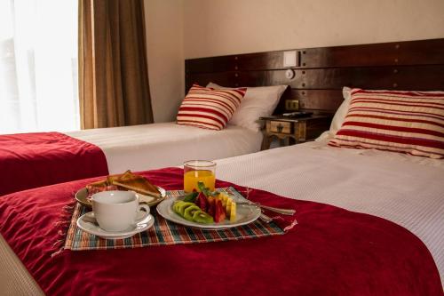 a breakfast tray with toast and fruit on a bed at Hotel El Molino in Santa Cruz