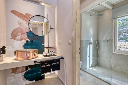 a bathroom with a shower and a sink and a mirror at Artblue Villas in Tsoukalades
