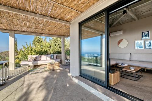 a living room with glass doors and a view of the ocean at Artblue Villas in Tsoukaladhes