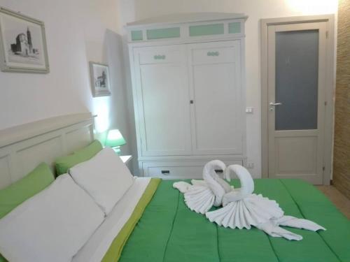 トラーパニにあるBilocale al Centroの白白鳥2羽が緑のベッドに座っている