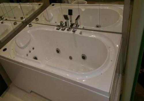 a white bath tub with a faucet in a bathroom at Rest Night Serviced Apartments- AlHamra in Riyadh