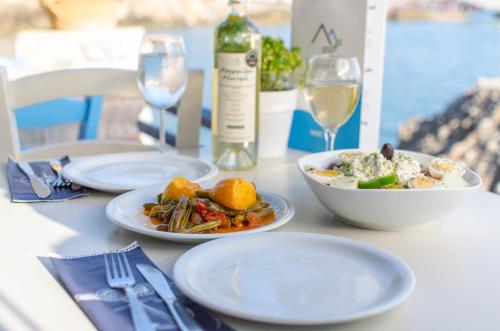 a table with plates of food and a bottle of wine at Lefka Ori in Khóra Sfakíon