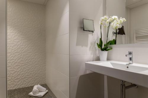 een witte badkamer met een wastafel en een spiegel bij The Originals City, Hôtel Armony, Dijon Sud (Inter-Hotel) in Chenôve