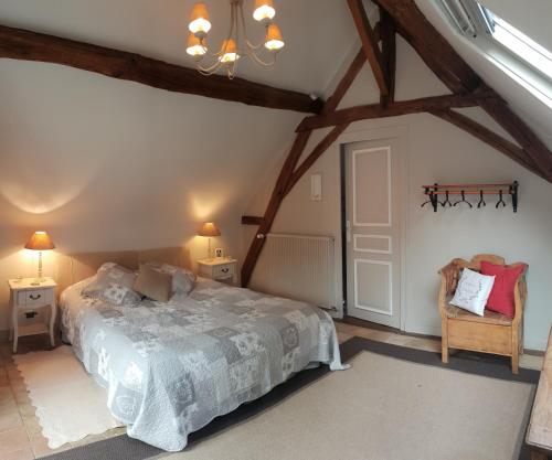 een slaapkamer met een bed en een stoel op zolder bij Au Clos du Coteau, Chambres d'Hôtes in Crotelles