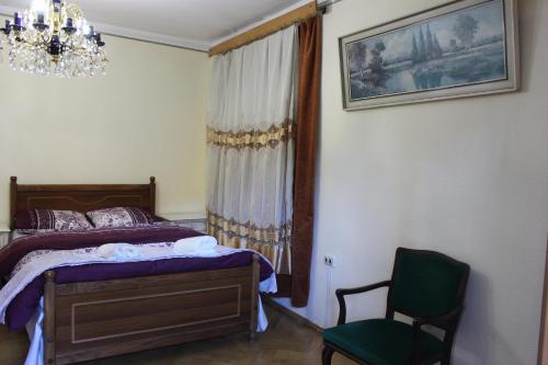 a bedroom with a bed and a chair and a chandelier at Old District Guest House in Tbilisi City