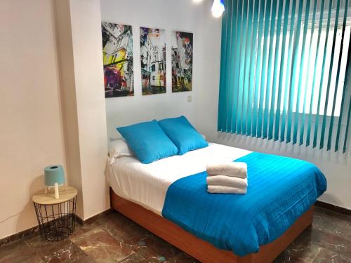 sypialnia z łóżkiem z niebieskimi poduszkami i oknem w obiekcie Apartamento Conde II w Saragossie