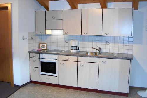 サースフェーにあるAkropolisの白いキャビネットとシンク付きのキッチン