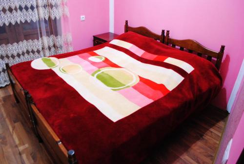 ein Bett mit einer roten und weißen Decke mit Tellern darauf in der Unterkunft Apartament GIORGI in Bordschomi