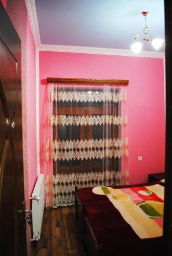 a pink room with a bed and a window at Apartament GIORGI in Borjomi