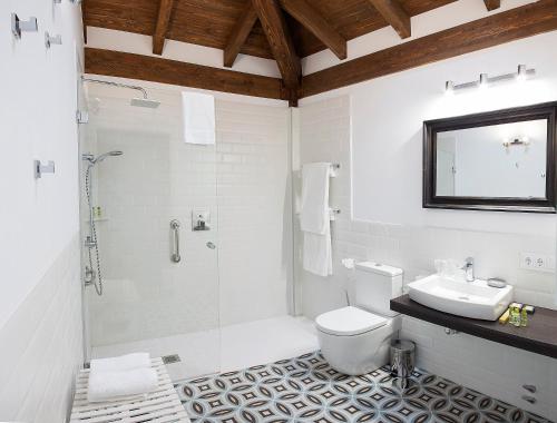 Ba&ntilde;o blanco con aseo y lavamanos en Hotel Rural 3 Cabos, en El Vallin