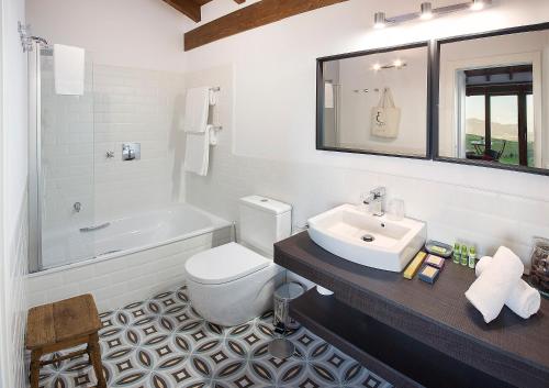 y baño con lavabo, aseo y bañera. en Hotel Rural 3 Cabos, en El Vallin