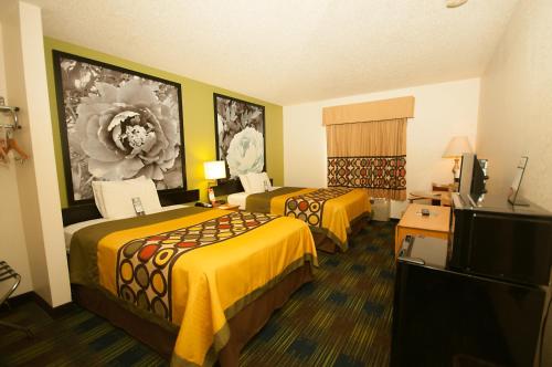 a hotel room with two beds and a flat screen tv at Super 8 by Wyndham Corydon in Corydon