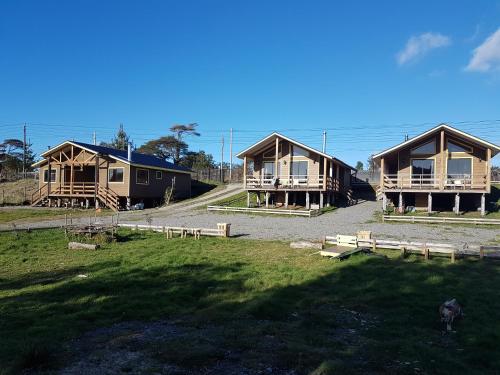 un groupe de cottages assis dans une prairie dans l'établissement Cabañas Torre Huillinco, à Huillinco