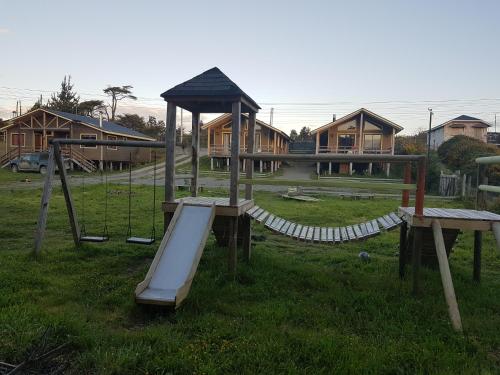 a playground with a slide and a swing set at Cabañas Torre Huillinco in Huillinco