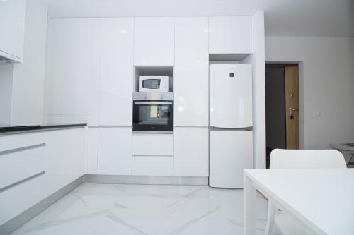 a white kitchen with a refrigerator and a table at Casas do Paço - Philosophy Apartments in Braga
