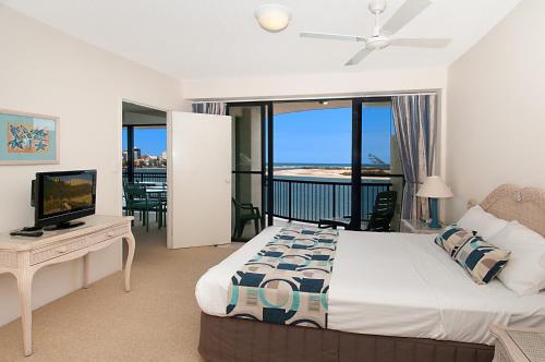 a hotel room with a bed, television, and couch at Windward Passage in Caloundra